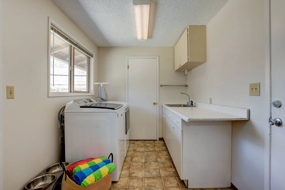A dedicated laundry area featuring a washing machine, sink, counter space, and a basket with colorful towels. The space is tidy and practical, perfect for organizing and managing gear after a day of adventuring.
